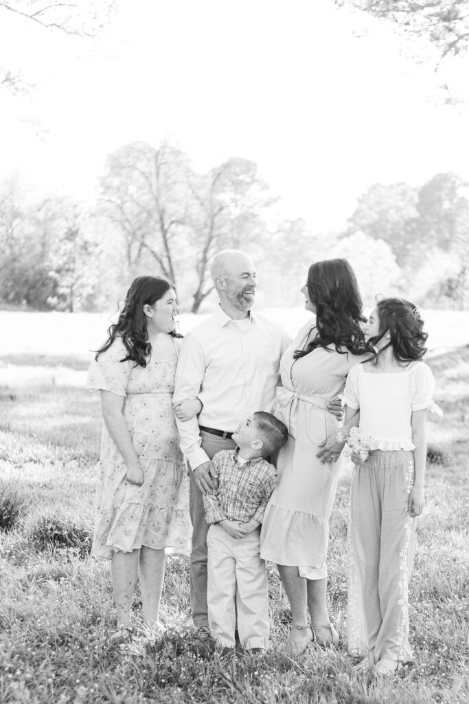 Family of 5 posing for spring photos in a field located in Hoover, Alabama.  Black and white photo, mom and dad looking at each other.