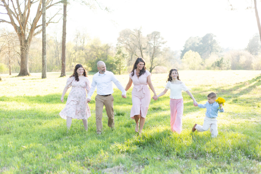 family of 5 holding hands and walking in a field located in birmingham, alabama